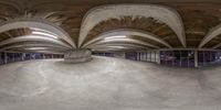 an indoor skate park has curved, exposed ceilings and floors as well as many skateboards