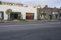 the shop is on the corner near the street side walk with shops on both sides