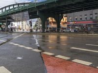 a bridge spans over an intersection of a busy city street with pedestrians crossing it in the background