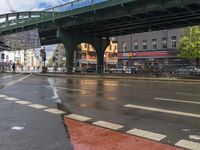 a bridge spans over an intersection of a busy city street with pedestrians crossing it in the background