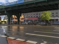 a bridge spans over an intersection of a busy city street with pedestrians crossing it in the background