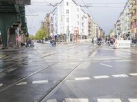 the street in front of a city building is wet and puddle - coated with a rain