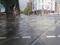 the street in front of a city building is wet and puddle - coated with a rain