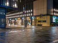 a large brick sidewalk with a store front at night time and a sign that says