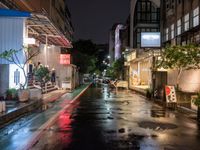 a wet city street is lit up at night as the rain starts to fall into the air