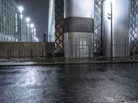 the wet city streets of a european area are very wet and dry at night with several buildings behind them