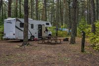 two motorhome tents set up next to picnic benches in the woods of an rv park