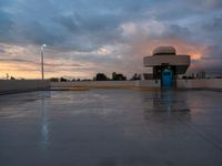 a wet parking lot and light tower in the sunset time during the day or night