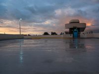 a wet parking lot and light tower in the sunset time during the day or night