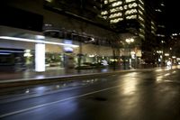 a blurry city street at night with a street lamp on it's side