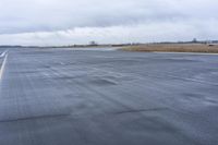 wet paved air taxiway at an empty airport on cloudy day and cloudy sky background