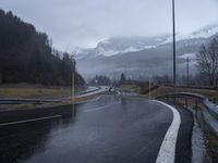 wet road with mountains in the distance and rain on the street and side in the foreground