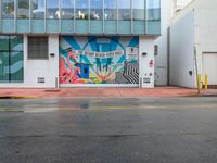 a stop sign is in front of an office building that has a large colorful mural on it