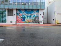 a stop sign is in front of an office building that has a large colorful mural on it