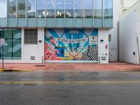 a stop sign is in front of an office building that has a large colorful mural on it