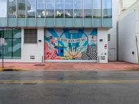 a stop sign is in front of an office building that has a large colorful mural on it