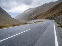 a motorcycle sits parked on a mountain road with a view across the mountains and the roadway