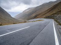 a motorcycle sits parked on a mountain road with a view across the mountains and the roadway