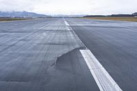 a wet runway with a road cut in the middle, with mountains in the background