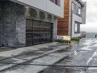 the sidewalk is wet from raining outside the building's glass doors in the rain