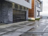 the sidewalk is wet from raining outside the building's glass doors in the rain