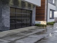 the sidewalk is wet from raining outside the building's glass doors in the rain