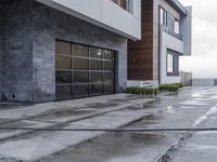 the sidewalk is wet from raining outside the building's glass doors in the rain