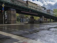 a bridge with an elevated walkway over a wet street in the city at day time