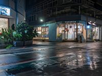 a wet street is outside of an office building at night with rain running down the road