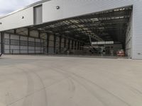 a white commercial aircraft is parked outside a hangar and a white car is parked inside a hangar