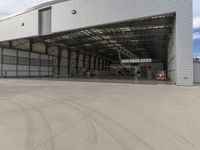 a white commercial aircraft is parked outside a hangar and a white car is parked inside a hangar