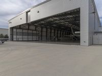 a white commercial aircraft is parked outside a hangar and a white car is parked inside a hangar