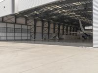 a white commercial aircraft is parked outside a hangar and a white car is parked inside a hangar