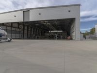 a white commercial aircraft is parked outside a hangar and a white car is parked inside a hangar