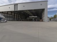 a white commercial aircraft is parked outside a hangar and a white car is parked inside a hangar