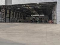 a white commercial aircraft is parked outside a hangar and a white car is parked inside a hangar