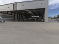 a white commercial aircraft is parked outside a hangar and a white car is parked inside a hangar