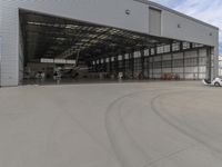 a white commercial aircraft is parked outside a hangar and a white car is parked inside a hangar