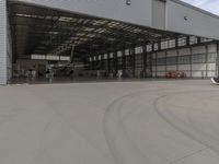 a white commercial aircraft is parked outside a hangar and a white car is parked inside a hangar