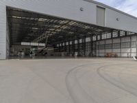 a white commercial aircraft is parked outside a hangar and a white car is parked inside a hangar