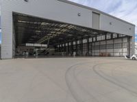 a white commercial aircraft is parked outside a hangar and a white car is parked inside a hangar