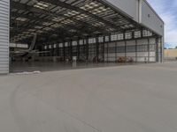 a white commercial aircraft is parked outside a hangar and a white car is parked inside a hangar