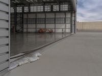 a white commercial aircraft is parked outside a hangar and a white car is parked inside a hangar