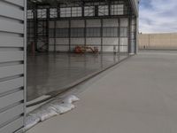 a white commercial aircraft is parked outside a hangar and a white car is parked inside a hangar