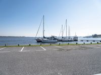 there are many white boats on the water side of the harbor dock in a parking lot