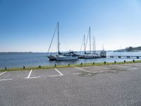 there are many white boats on the water side of the harbor dock in a parking lot