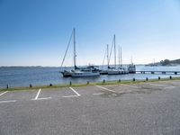 there are many white boats on the water side of the harbor dock in a parking lot