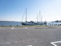 there are many white boats on the water side of the harbor dock in a parking lot