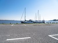 there are many white boats on the water side of the harbor dock in a parking lot