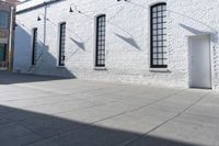 two windows that are on a white brick building with a gray sidewalk and a red fire hydrant